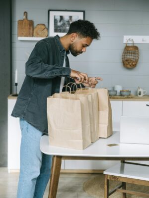 Young man organizing paper shopping bags indoors in a modern kitchen setting.
